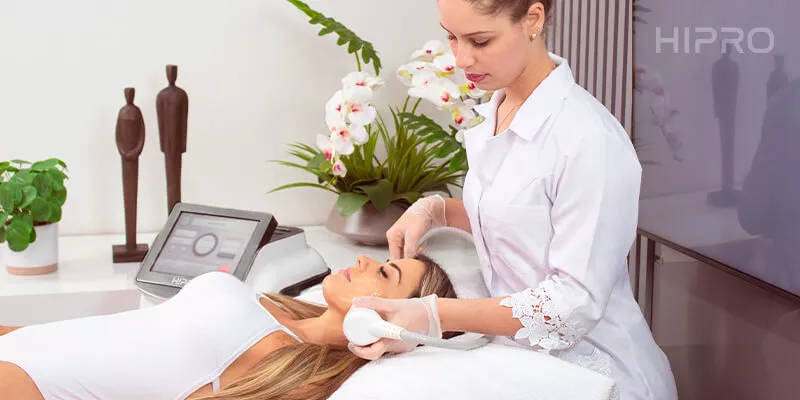 Mulher deitada e aplicadora fazendo o ultrassom microfocado na região facial.