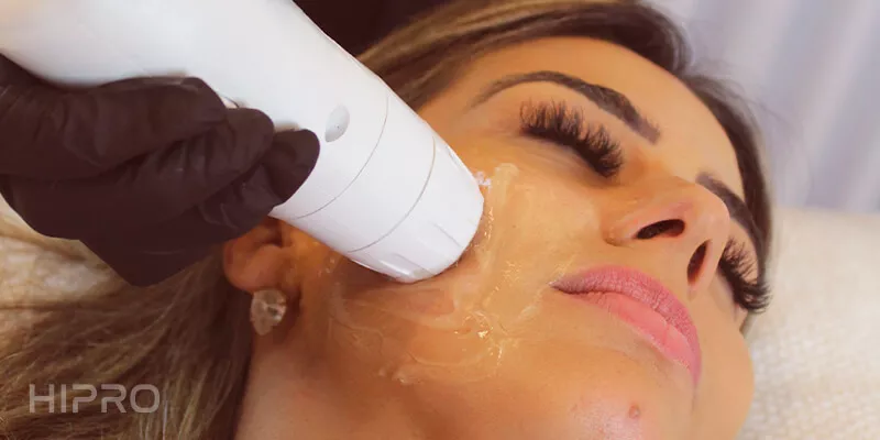 Modelo deitada de olhos fechados fazendo tratamento facial com o aparelho de estética facial HIPRO